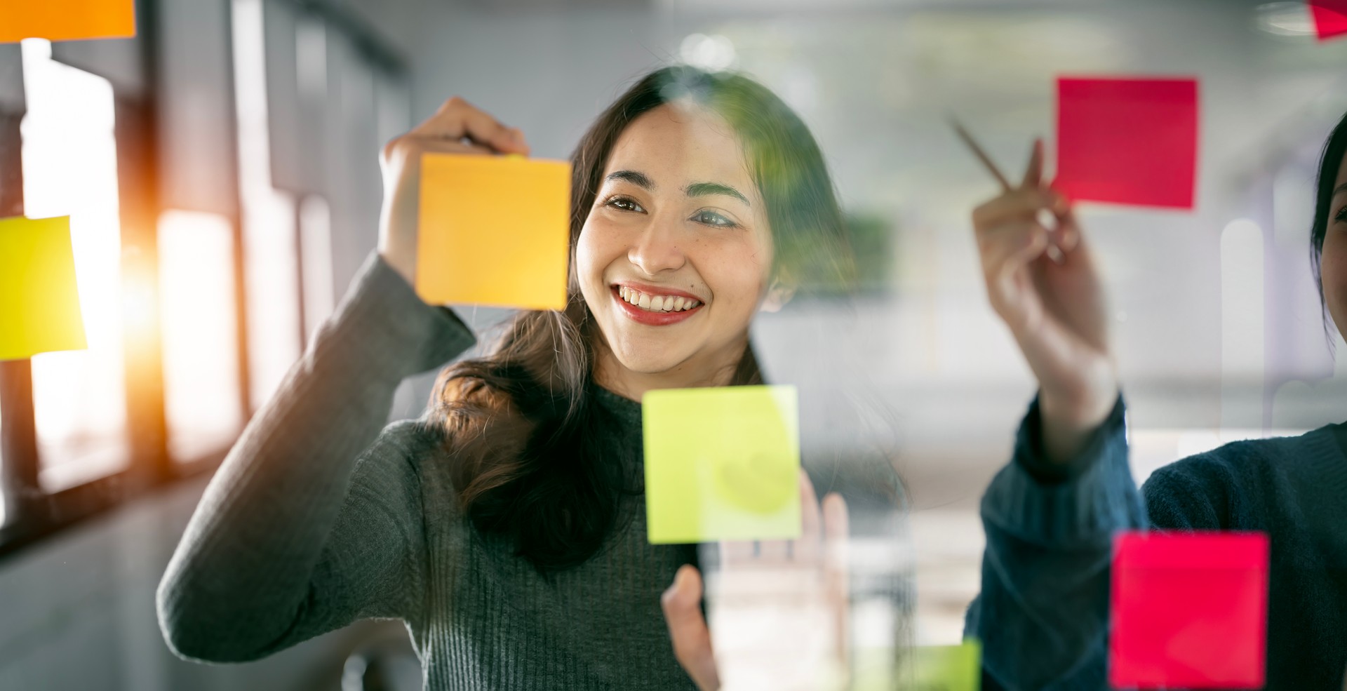 Young  businesswoman creative team using post it notes in glass wall to writing strategy business plan to development grow to success.